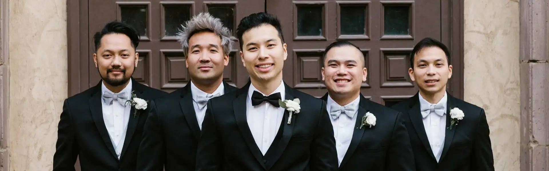 Wedding party in all black tuxedos in a line.